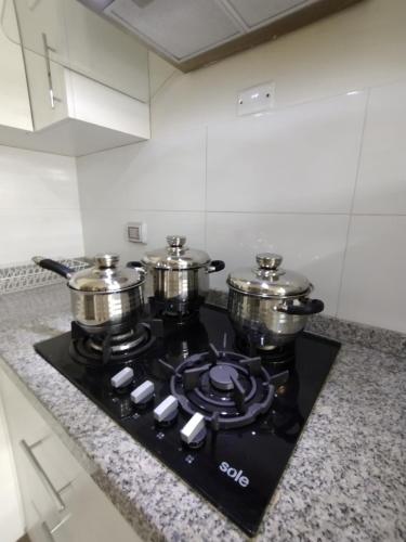 a stove top with pots and pans on top of it at Suites Apart Piura in Piura