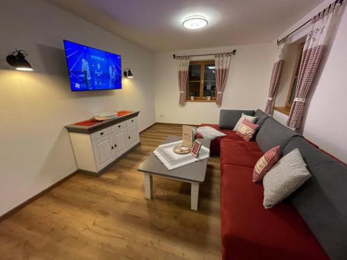 a living room with a couch and a tv at Ilgerhof Ferienwohnungen in Oberaudorf