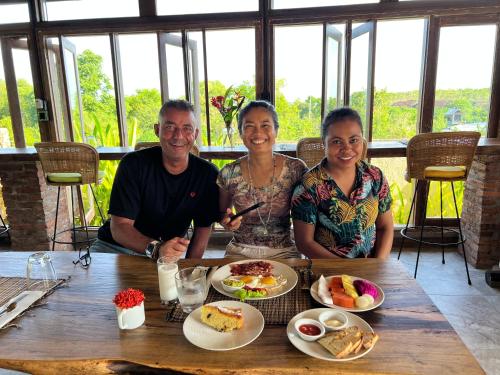 a group of three people sitting at a table with food at PINOKKIO B&B Restaurant in Jimbaran
