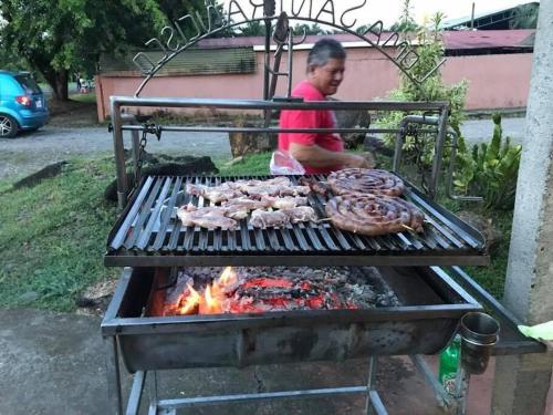 a woman is cooking meat on a grill at Retana Apartment in Quesada