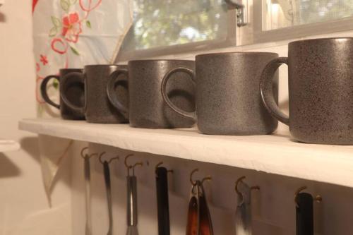 una fila de tazas de café grises sentadas en un estante en Eucalyptus Cabin Boquete en Bajo Boquete