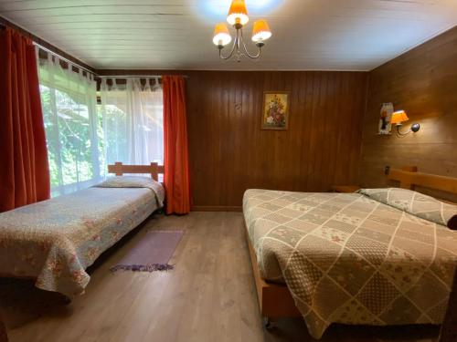 a bedroom with two beds and a window at Hostal el Nogal Pucón in Pucón