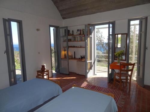 a bedroom with two beds and a desk and sliding glass doors at Ageranos in Vathi