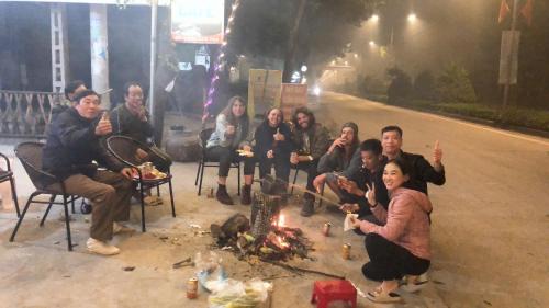 um grupo de pessoas sentadas à volta de uma fogueira à noite em Tam Coc Scenery Homestay em Văn Lâm