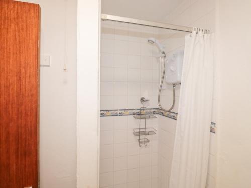 e bagno con doccia con tenda bianca. di Primrose Cottage a Paignton