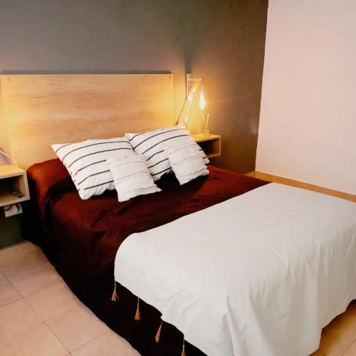 1 dormitorio con 1 cama con sábanas y almohadas blancas en DEPARTAMENTO EN EL CENTRO DE TANDIL en Tandil