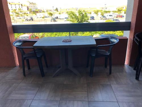 une table et deux chaises devant une fenêtre dans l'établissement Appartement T2 climatisé avec piscine et parking à Port Barcarès - FR-1-81-402, au Barcarès