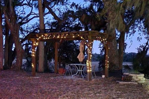 a wooden pergola with a table and lights at Secluded Tiny House by the Marsh with Hunting Island Beach Pass in St. Helena Island