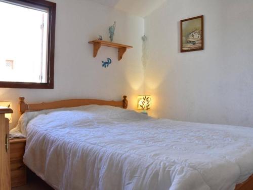 une chambre avec un lit avec un couvre-lit blanc dans l'établissement Pavillon 3 pièces à Gruissan avec piscine, 2 terrasses et parking privé, à 400m de la mer - FR-1-229-842, à Gruissan