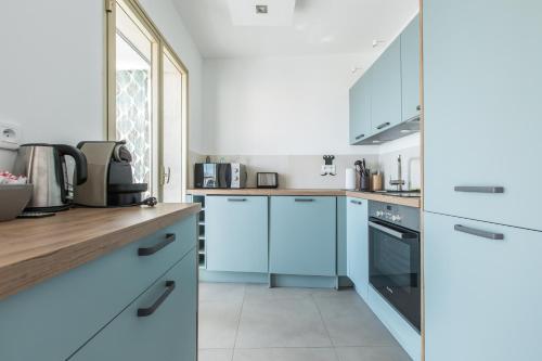 une cuisine avec des armoires blanches et des appareils bleus dans l'établissement LB Vacation Rentals I Admire Panoramic Ocean Views Through Walls of Windows, à Cannes