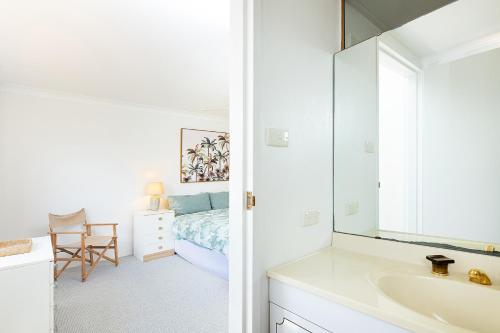 a bathroom with a sink and a bedroom with a bed at Braemar 3 in Forster