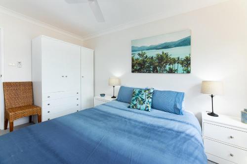a white bedroom with a blue bed and a chair at Braemar 3 in Forster