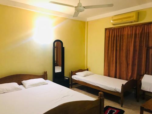 a bedroom with two beds and a ceiling fan at Green Parrot Family Resort in Polonnaruwa