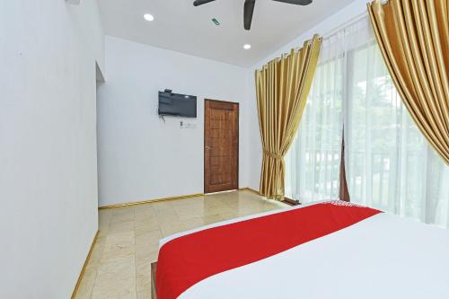 a bedroom with a red and white bed and a window at Hotel O Jentayu Homestay Pontian in Pontian Kecil