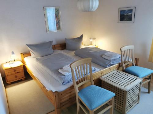ein kleines Schlafzimmer mit einem Bett und zwei Stühlen in der Unterkunft Haus Juist - Schillig in Wangerland