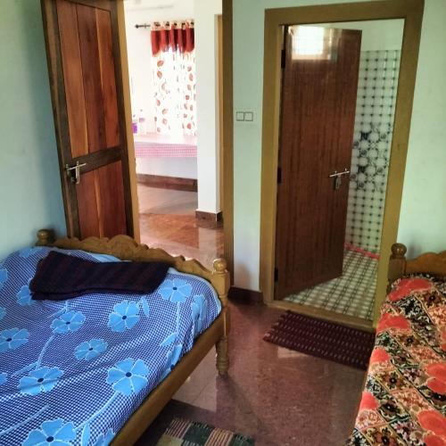 a bedroom with a bed and a mirror at GOLDEN HILL HOMESTAY WAYANAD in Panamaram
