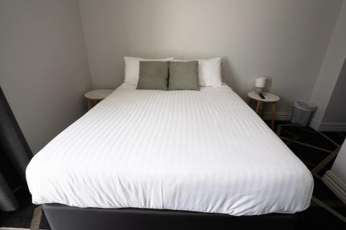 a large white bed in a room with two tables at Sports Garden Hotel in Launceston
