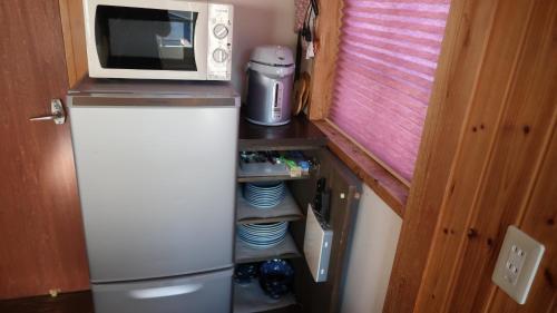 a small kitchen with a microwave and a refrigerator at Kuranoyado Matsuya in Fujikawaguchiko