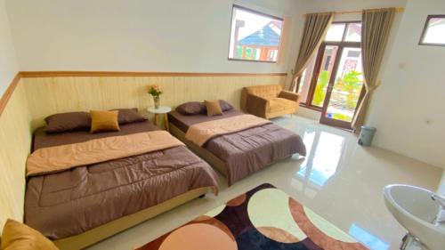 a bedroom with two beds and a chair at Madinna Villa Dieng in Dieng