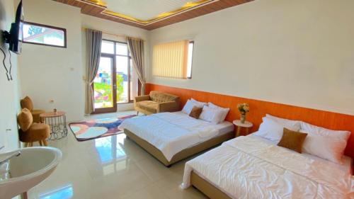 a bedroom with two beds and a bathroom with a sink at Madinna Villa Dieng in Dieng