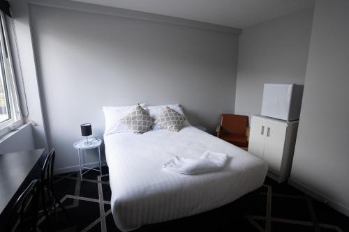 a bedroom with a bed with white sheets and pillows at Sports Garden Hotel in Launceston