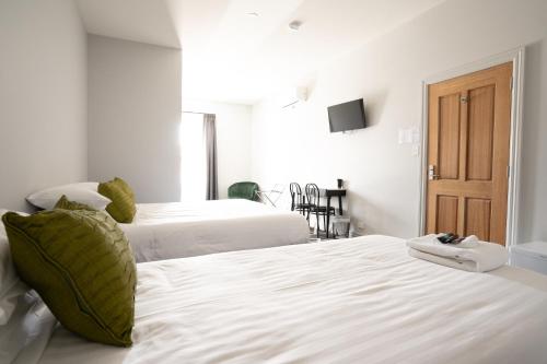 a bedroom with two beds with white sheets and a door at Sports Garden Hotel in Launceston