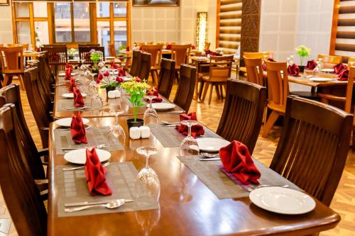 a long table in a restaurant with red napkins and tables at Tara Phendeyling Hotel in Thimphu