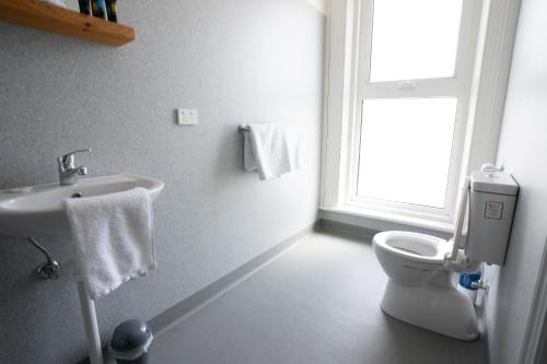 a bathroom with a toilet and a sink and a window at Sports Garden Hotel in Launceston