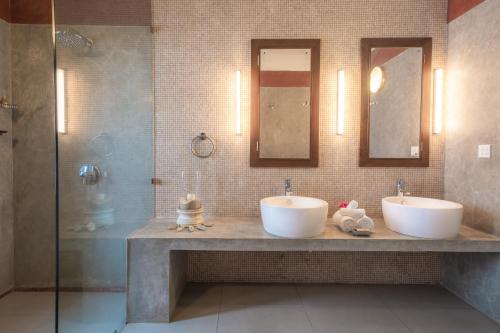 2 lavandini in un bagno con due specchi e una doccia di Kabalana House by Ceilao Villas ad Ahangama