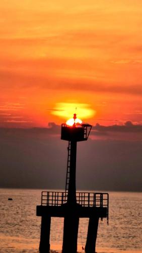 a lighthouse on the beach with the sunset in the background at Haadrin Village near the pier in Haad Rin