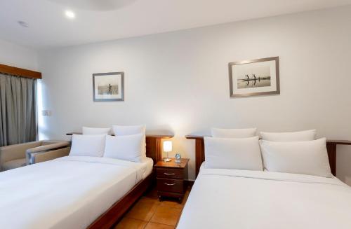 two beds in a hotel room with white sheets at Airways Hotel in Port Moresby