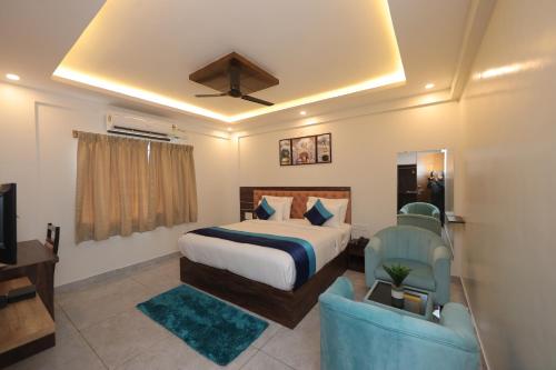 a bedroom with a bed and a chair and a television at VOVO HOTELS in Yelahanka