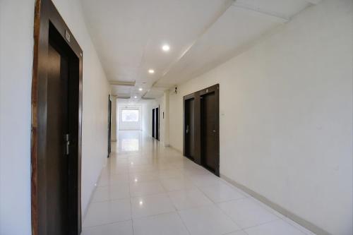 un couloir vide avec des portes noires et du carrelage blanc. dans l'établissement FabExpress Aditya Regency-Near Railway Station-Bhopal, à Bhopal