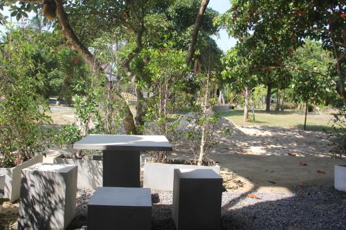 a table and chairs in a park with trees at Yangyai Garden Lodge in Baan Tai