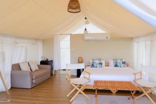 a bedroom with a bed and a couch and a table at SOL Glamping at Khao yai in Ban Nong Makha