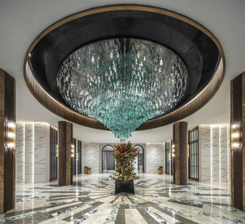 a large chandelier hangs from the ceiling of a lobby at Fili Hotel at Nustar Cebu in Cebu City