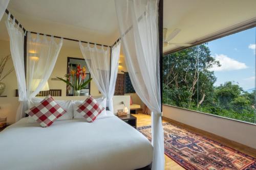 a bedroom with a bed and a large window at Ambong Rainforest Retreat in Pantai Cenang