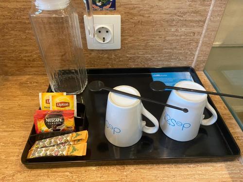 a tray with two coffee mugs and snacks on it at Desatu Hotel in Medan