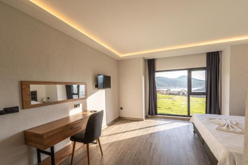 ein Hotelzimmer mit einem Bett, einem Schreibtisch und einem Fenster in der Unterkunft Tolstoy'un Bisikleti Otel in Gokceada Town
