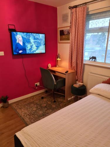 a bedroom with a desk and a tv on a red wall at BABUS INTL in Cranford