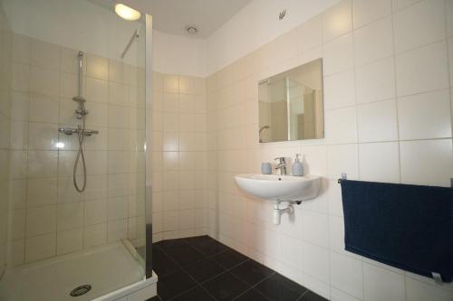 een witte badkamer met een wastafel en een douche bij CityView Apartment including parking in Rotterdam
