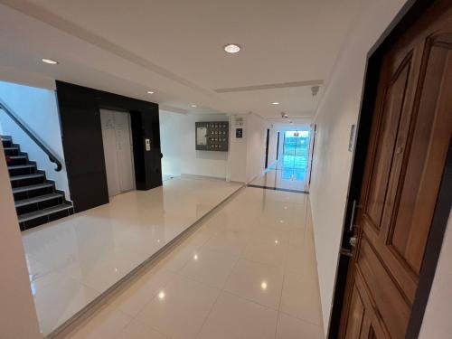 a hallway with white floors and a door and stairs at The Joke Mansion เดอะโจ๊ก แมนชั่น สุขุมวิท 23 มาบตาพุด ระยอง in Ban Map Ta Put
