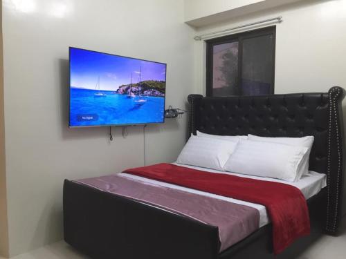 een slaapkamer met een bed en een tv aan de muur bij THE VISTA BRENT HILL BAGUIO in Baguio