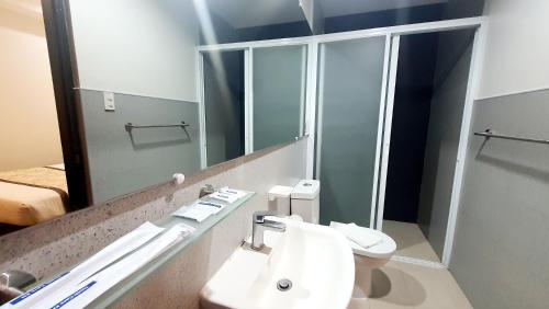 a bathroom with a toilet and a sink and a mirror at Vianshe Hotel in Tagaytay