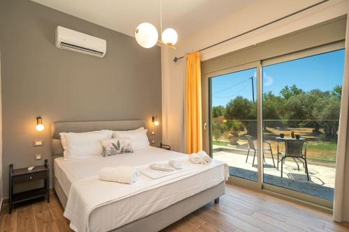 a bedroom with a bed and a balcony with a table at Luxury Villa Majore in Svoronata