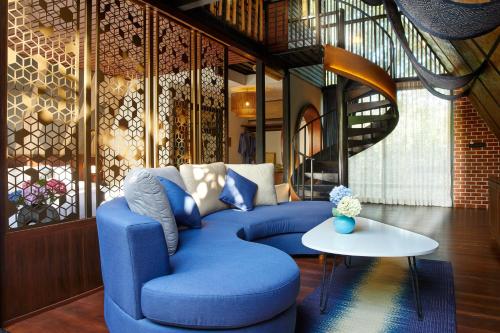 a living room with a blue couch and a table at LA COCOTTE VILLA & FARM KHAO YAI in Nong Sarai