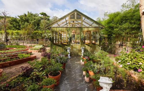 a greenhouse in a garden with potted plants at LA COCOTTE VILLA & FARM KHAO YAI in Nong Sarai