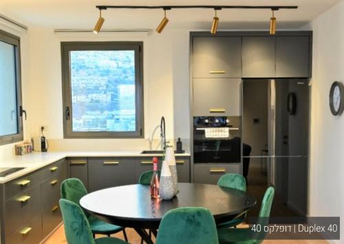 a kitchen with a table and green chairs at YalaRent La Mera- Suits Hotel with Sea of Galilee views in Tiberias