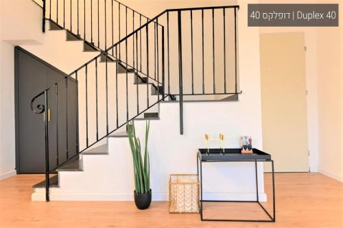 a staircase with black railings in a living room with a table at YalaRent La Mera- Suits Hotel with Sea of Galilee views in Tiberias