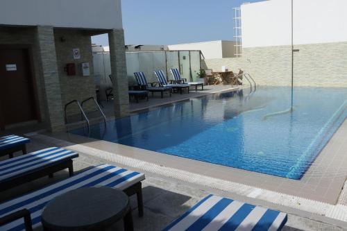 a large swimming pool with blue and white striped chairs at Strato Hotel By Warwick in Doha